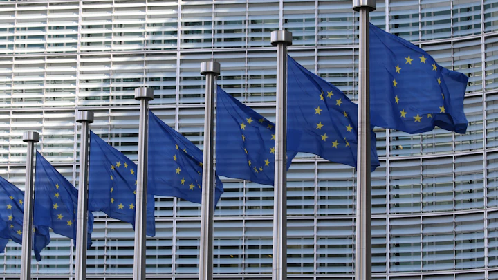 A row of European Union flags in front of the Berlaymont building in Brussels